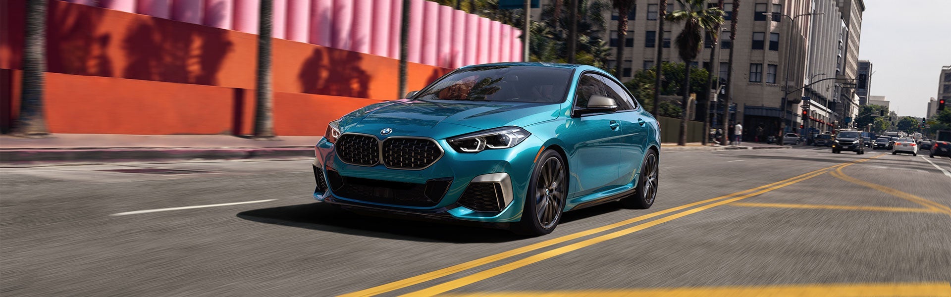 A blue metallic BMW 2 Series Gran Coupe driving down street during the day.