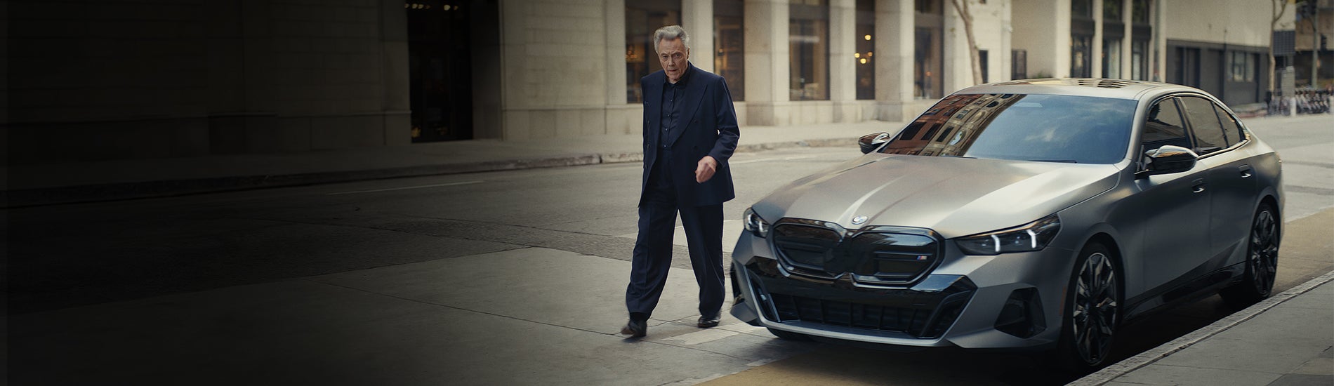 Christopher Walken walking around a BMW 5 Series.