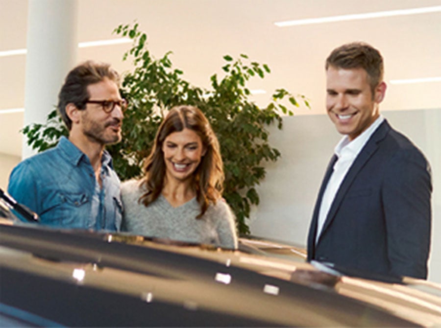 A dealer at a BMW Center speaks with a couple in front of a BMW